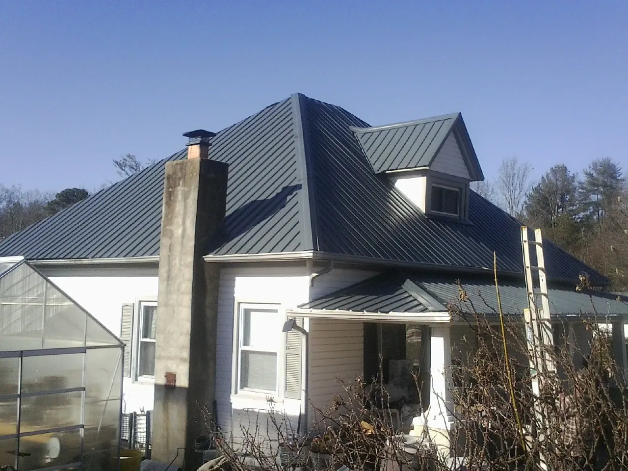 Dark blue standing seam metal roof on a white farmhouse with dormer — Slate & Tile Roof Repair by Roofing Brothers in Worthington